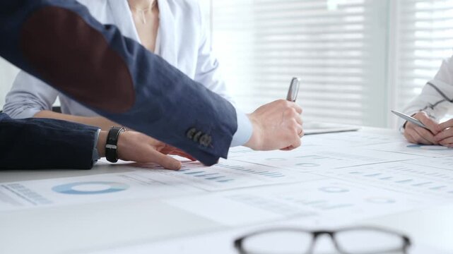 Businesswoman signing important contract documents at a meeting. Confirming agreement and partnership details while colleagues show support