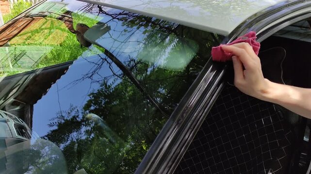 Woman washing car with rag, wiping vehicle with cloth
