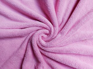 Soft pink fleece fabric texture background twisted in a spiral vortex shape. © Albip