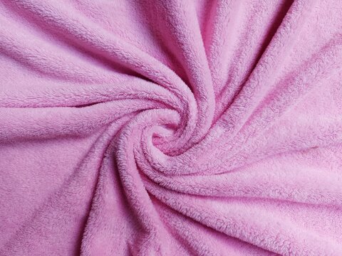 Soft pink fleece fabric texture background twisted in a spiral vortex shape.