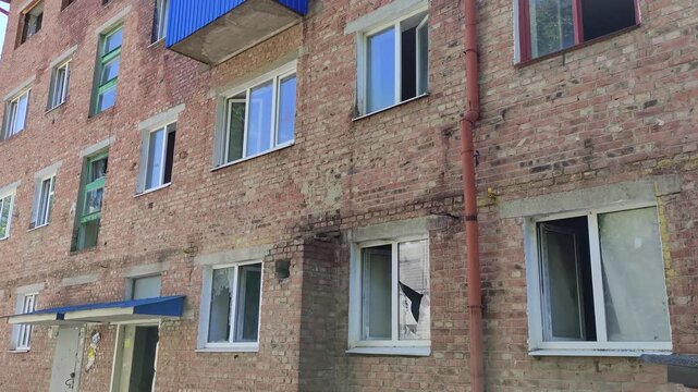 Close up of old abanoned brick apartment building with blue balcony and broken windows