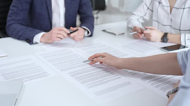 Business people discussing contract terms, outlining agreements, and reviewing legal documents during a corporate meeting, preparing for a significant partnership signing and negotiation
