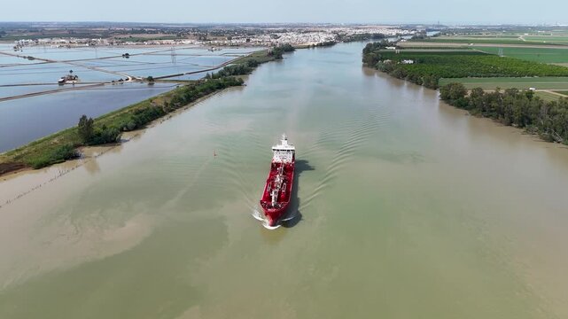 Aerial view of red oil tanker sailing down the Guadalquivir river