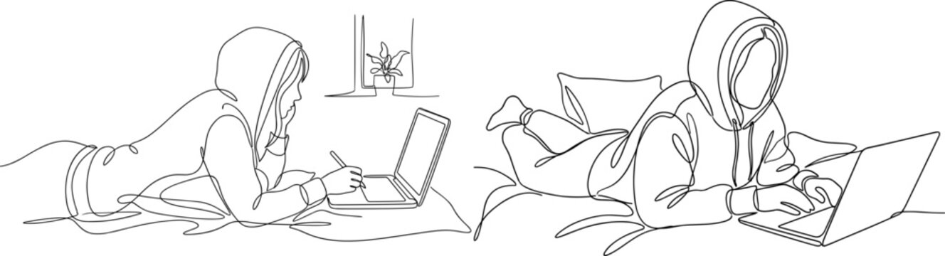 Two people wearing hoodies lying on the floor working on laptops.