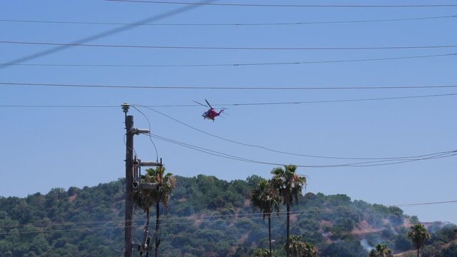 Slow motion shot of Los Angeles Fire Department responding to wildfire with aerial unit dropping water 