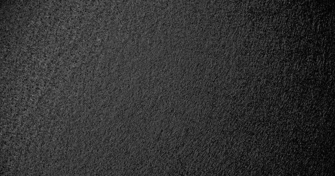 Slow Rotation Over Black Texture. Smooth rotation across extreme close-up of fine black pebbled surface with dramatic side lighting.