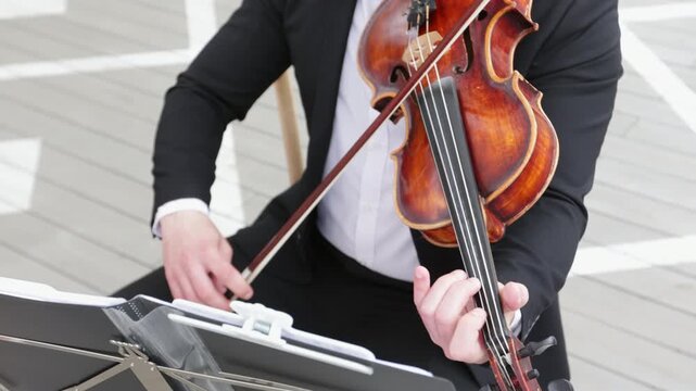 Close up of a bearded male musician in a black suit playing classical violin