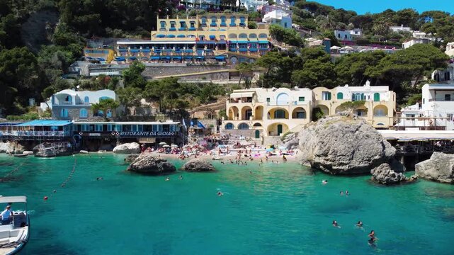 Cinematic aerial view of Capri Marina Piccola with boats and coastal cliffs