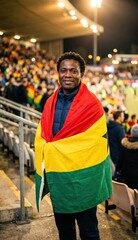 Fototapeta premium Ghana football supporter wrapped in national flag at stadium