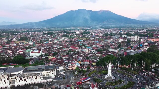 Aerial drone view of Bukittinggi city with Mount Marapi volcano in the background, scenic cityscape of West Sumatra Indonesia surrounded by tropical highlands and traditional Minangkabau landscape
