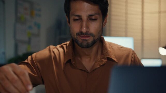 Sleepy young Latin businessman yawning over heavy paperwork stack at desk in dark night office. Overwork burnout, working late overtime, corporate job stress, exhausted professional manager concept.
