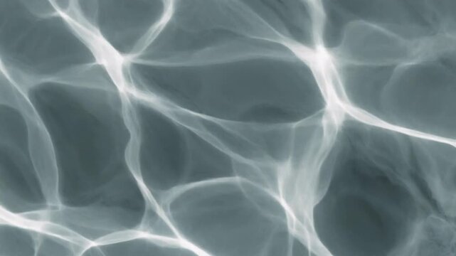 Abstract water ripples and reflections on a surface, creating a mesmerizing and fluid pattern with light and shadow