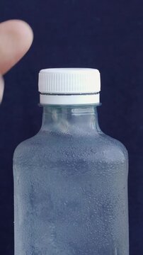 A man's hand closing the cap of a plastic bottle containing clean water.Water benefits for skin and health