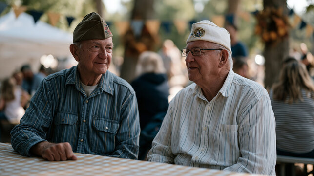World War Two veteran and Labor Day parade organizer sitting together at a community barbecue table, reminiscing over a framed photograph of a local factory wartime workforce, families gathered arou
