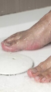 Close-up of male feet taking a shower and dancing in the bathroom
