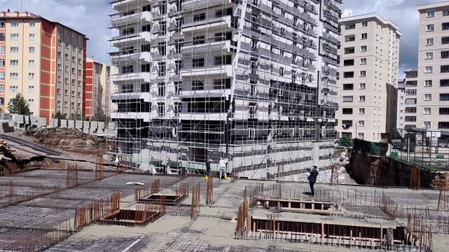 Vertical static shot capturing the dense steel reinforcement rebar grids and utility trenches inside a building foundation excavation pit.