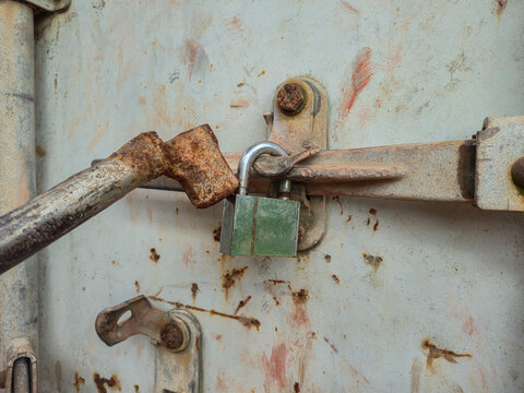 ​Forced open padlock with iron rod on rusty metal container door, security breach, break in and lockpicking concept
