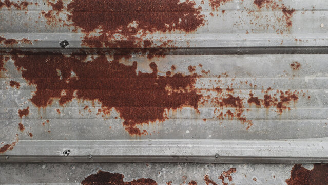 Rusty corrugated metal sheet texture background. Natural rustic background of weathered galvanized iron wall under bright outdoor daylight