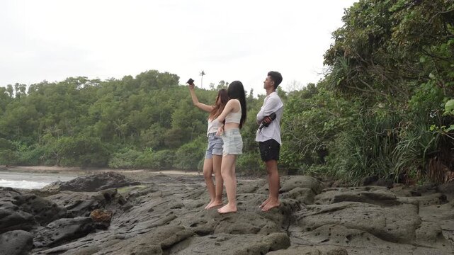 Friends Taking Selfie on Coastal Rocks in Yogyakarta Indonesia