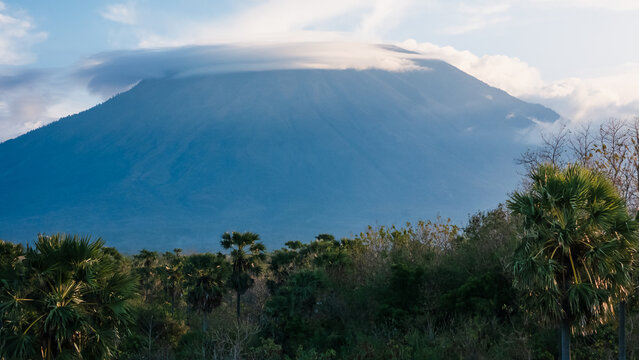 Volcanic mountain rising above tropical forest under cloudy sky in Bali