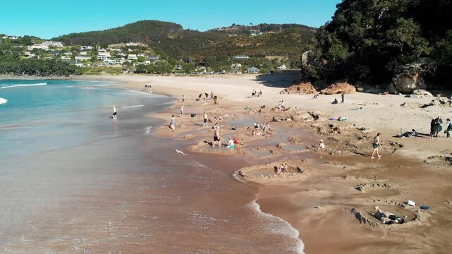 COROMANDEL, NEW ZEALAND - AUGUST 2018: Tourists enjoy the beautiful Hot Water Beach on a sunny day, slow motion