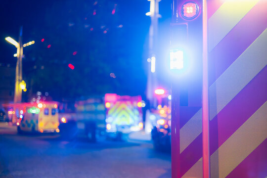 Flashing fire trucks and ambulance on city street at night during emergency response. Fire, accident scene, rescue operation and public safety concept.