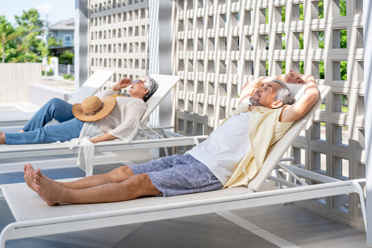 active asian senior friends resting on lounge chairs together at poolside, elderly people lifestyle travel on summer vacation