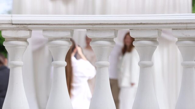 View through a white balustrade of a wedding photographer working with guests