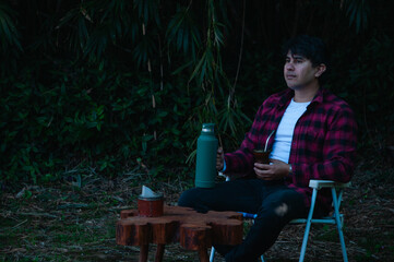 persona joven bebiendo mate en el jardín o el parque. hombre contemplando el paisaje y con expresión de tranquilidad y calma © Daniel