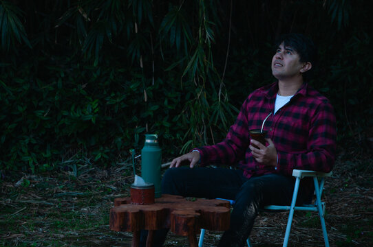 persona joven bebiendo mate en el jard&iacute;n o el parque. hombre contemplando el paisaje y con expresi&oacute;n de tranquilidad y calma