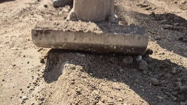 Front view shot of soil compaction at a construction site using a handheld power rammer compactor machine.