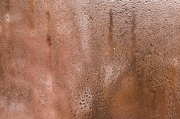 Fototapeta premium Condensation on window glass forming wet pattern, droplets reflecting diffused light, closeup detail of wet surface, abstract urban and natural background concept