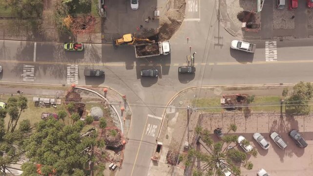 Top down aerial view of urban intersection reconstruction with excavator and traffic flow