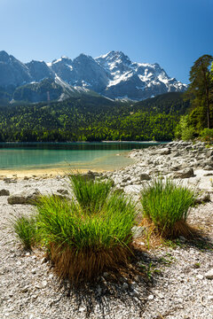 Travel landscape of Eibsee lake and Zugspitze mountains peak Alps in Bavaria Germany, scenic summer nature panorama with forest and beach