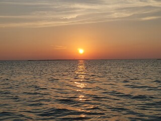 Fototapeta premium Beautiful golden sunset over the calm ocean horizon with sun reflection on water