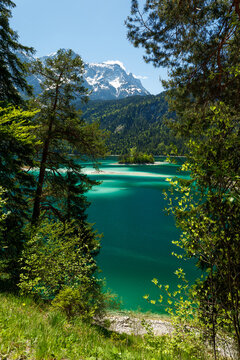 Travel landscape of Eibsee lake, island and beach and Zugspitze mountain peak in Alps, Bavaria, Germany, scenic summer nature panorama with forest