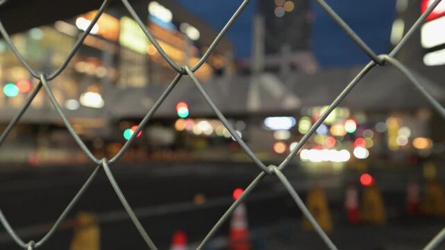 道路工事の金網の先に見える都市の夜景