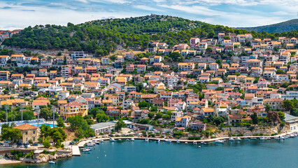Obraz premium Scenic view of a coastal town in Croatia with houses on a hillside overlooking the Adriatic Sea and a small harbor