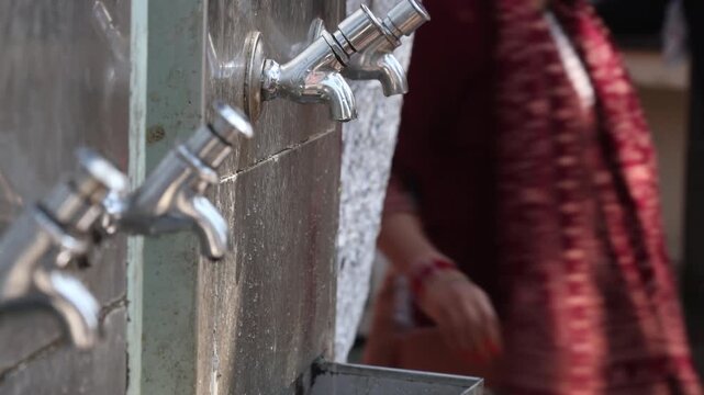 Raw video footage of stainless steel water taps installed at a Hindu temple for drinking water and hand washing after free community meals in rural India temple premises.