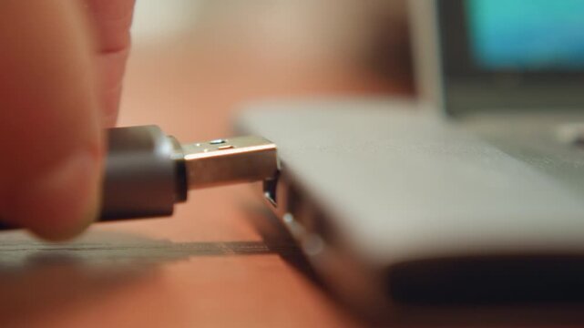 Closeup laptop port while hand inserts usb anxious student racing deadline, late night lamp glow on desk, scattered notes blurred in background, tense fingers, quick insert and save motion