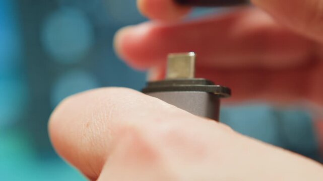 Blue light supports connection. Close up of hands securing connection with glowing indicator. Technician ensures stable connection by tightening adapter while background displays blue glow