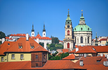 Obraz premium St. Nicholas Church and Strahov Monastery Rising Above Red Rooftops in Prague