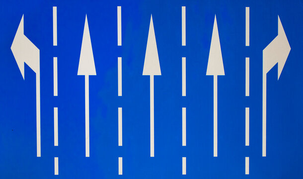 Blue road sign with white traffic direction arrows