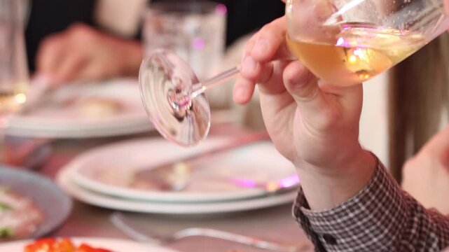 Close up of a hand swirling white wine in a glass at a restaurant banquet