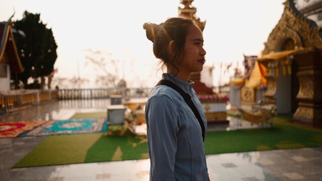 Young woman visiting buddhist temple in chiang mai, thailand at sunset
