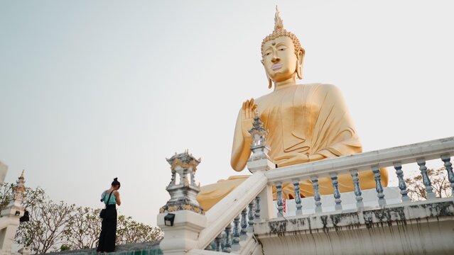 Golden buddha statue at thai temple. Woman admiring cultural heritage in chiang mai