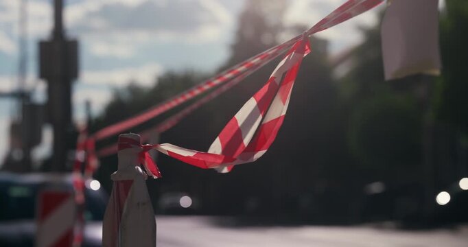Red and white safety tape stretched across a city street on a sunny day during Labor Day holiday.