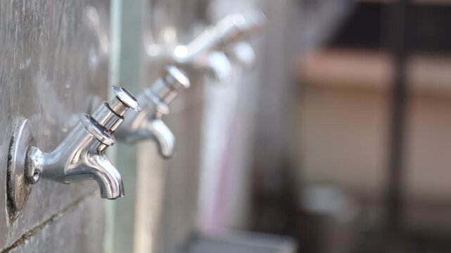 Raw video footage of stainless steel water taps installed at a Hindu temple for drinking water and hand washing after free community meals in rural India temple premises.