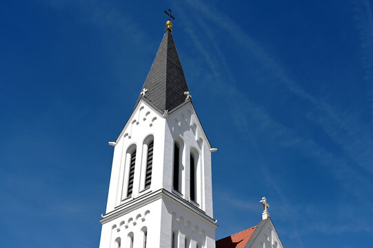 church bell tower. low angle elevation. the city of Veszprem, Hungary. white stucco exterior wall finish. steep sloped roof. Christian cross on top. travel, tourism, architecture and religion concept