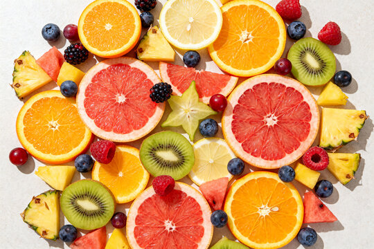 Assorted fresh sliced citrus and tropical fruits on light background